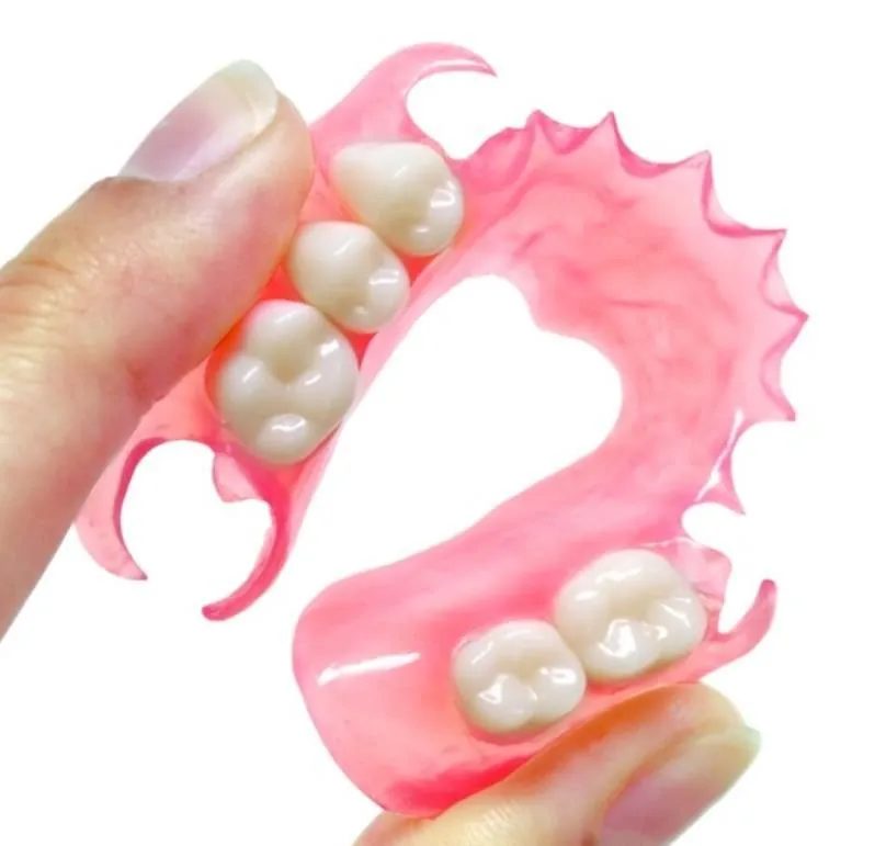 A flexible partial denture bent between two fingers